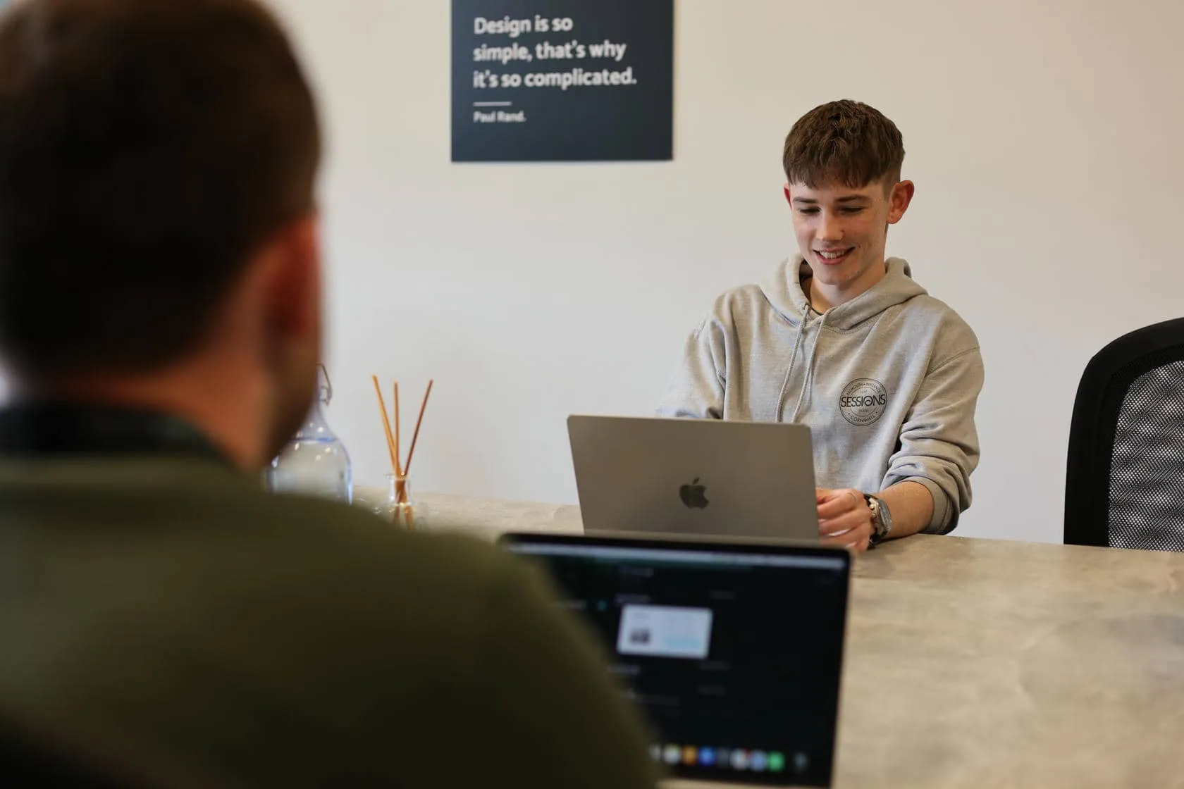 A UX designer working on a laptop on an office boardroom