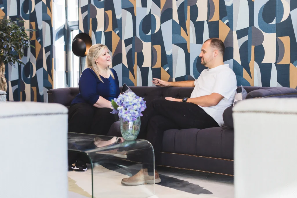 Sarah and Adam Smith sat on an office sofa having a conversation