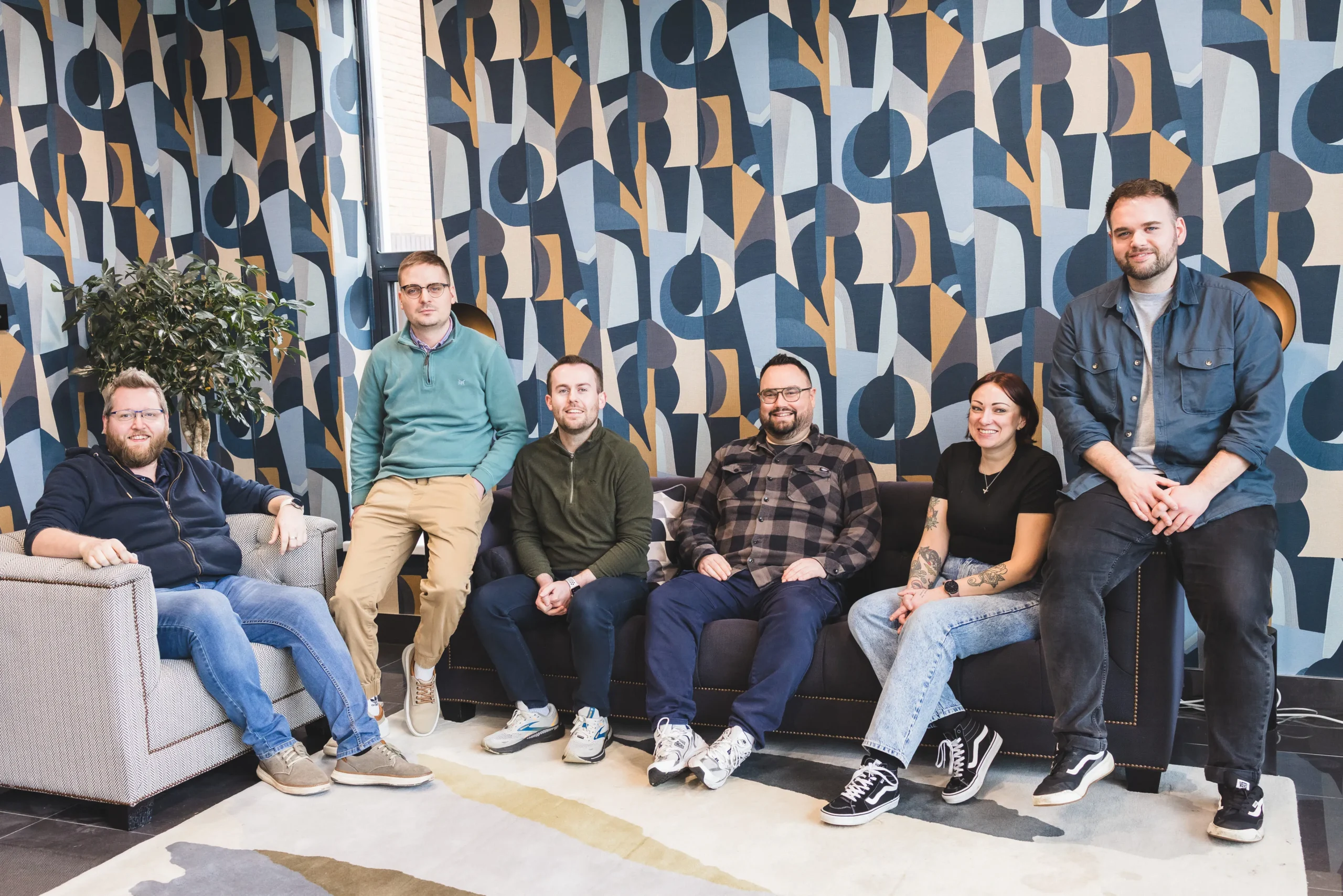 Damteq's line management team sat on sofas in the reception of the office building smiling at the camera