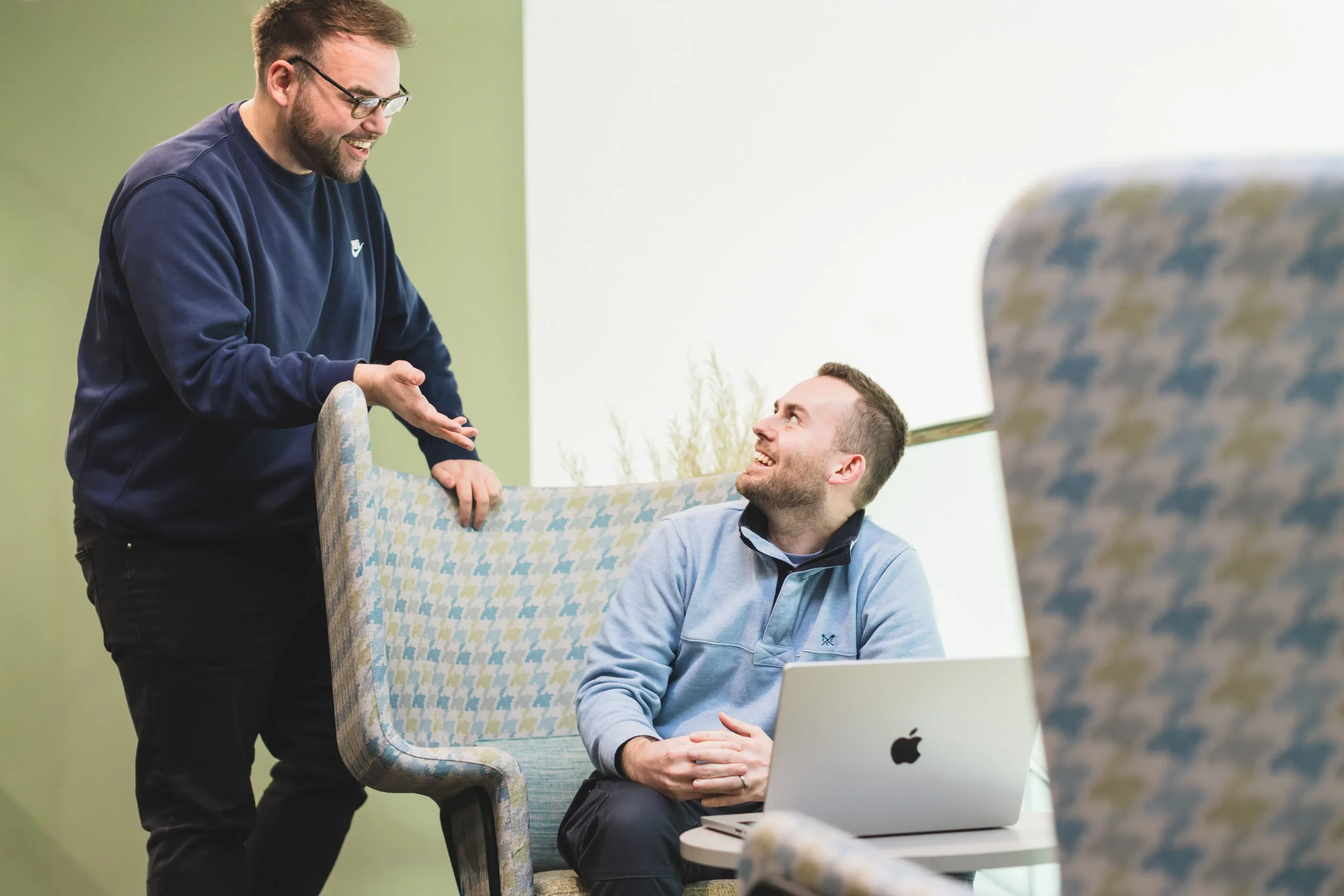 Josh working in the atrium with Adam leaning over his chair to watch