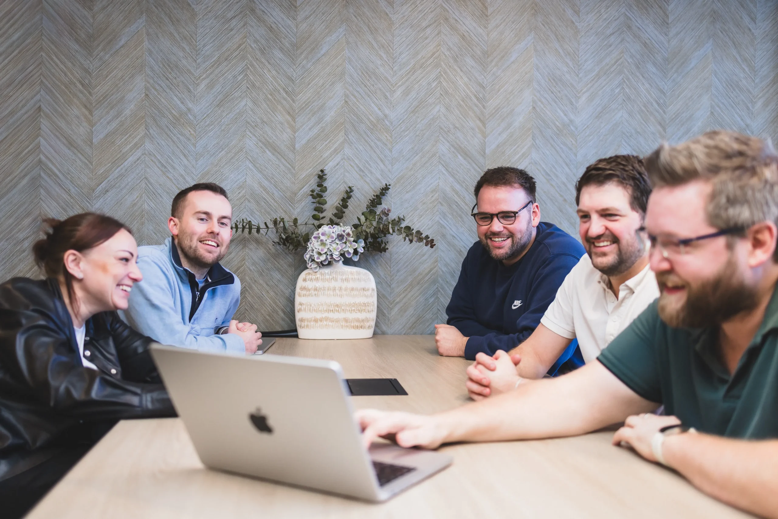 Damteq's Marketing and Web Specialists collaborating around two laptops on a table.