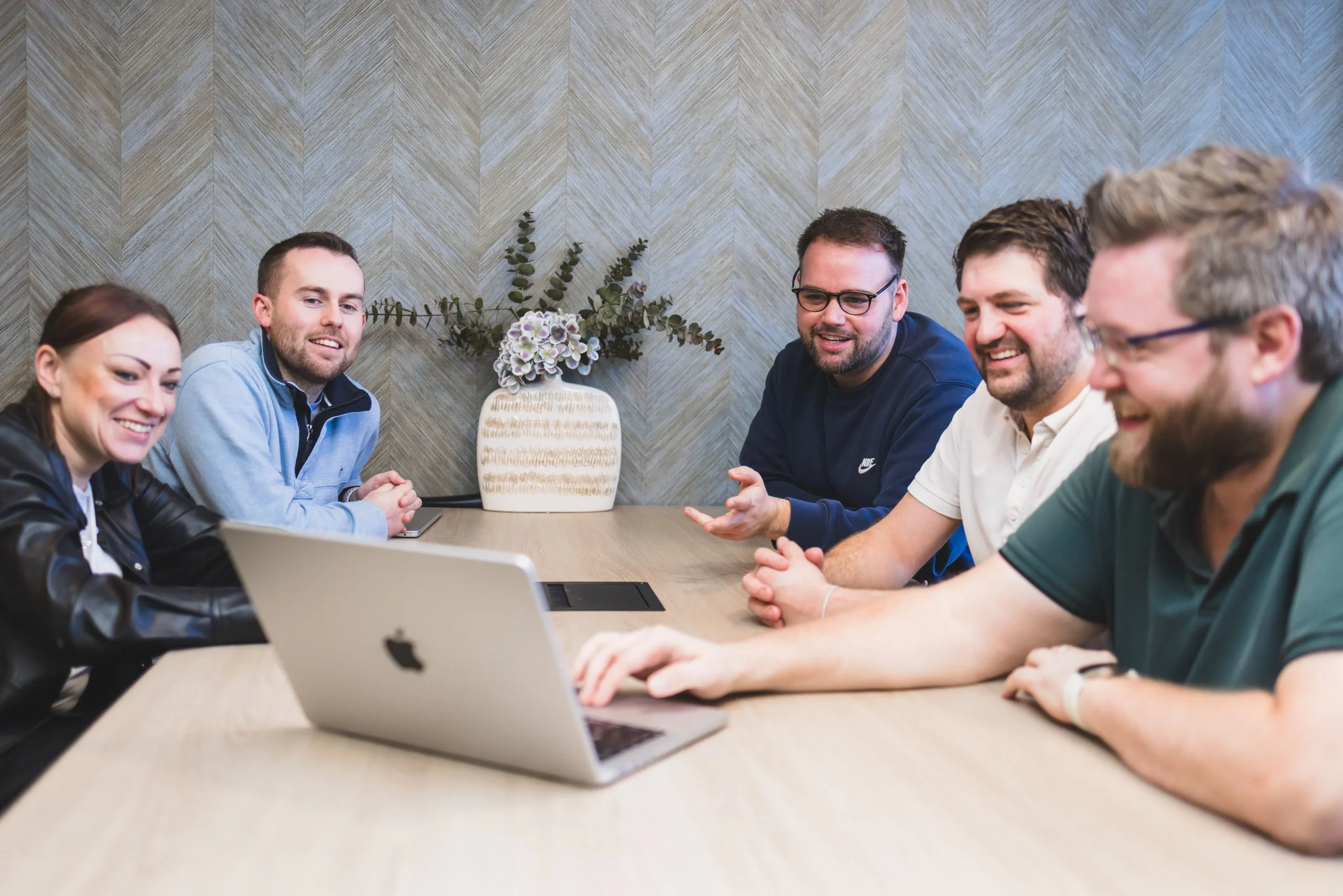 Damteq's Marketing and Web Specialists collaborating around two laptops on a table.
