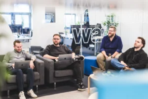 Four people in the Damteq Web team sat having a meeting with their laptops on the office sofas